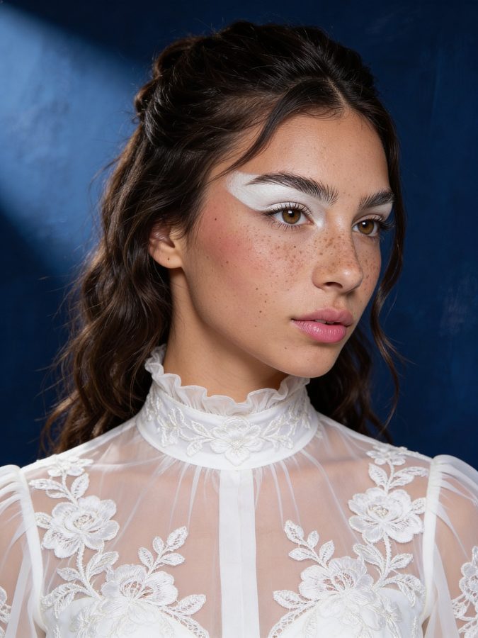 Photoreal AI editorial profile picture: white lace blouse, graphic liner, navy studio backdrop